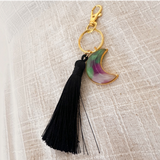 Luna Glow moon keychain in translucent resin with purple and green swirls, gold hardware and a long black tassel