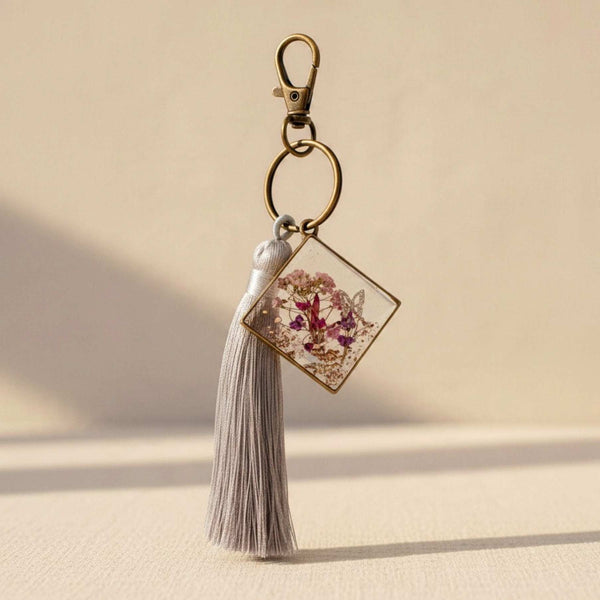 Meadow Butterfly pressed flower bag charm in a bronze square frame with pink and purple blooms and a grey tassel