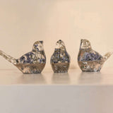 Memorial resin bird with ashes shown as three clear resin songbirds with blue flowers and metallic gold flecks