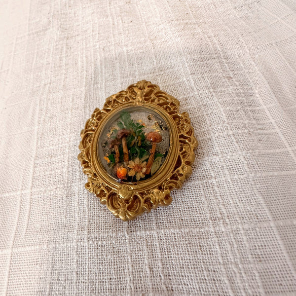 Mushroom fridge magnet with a dried daisy and orange bloom along the base of the forest scene