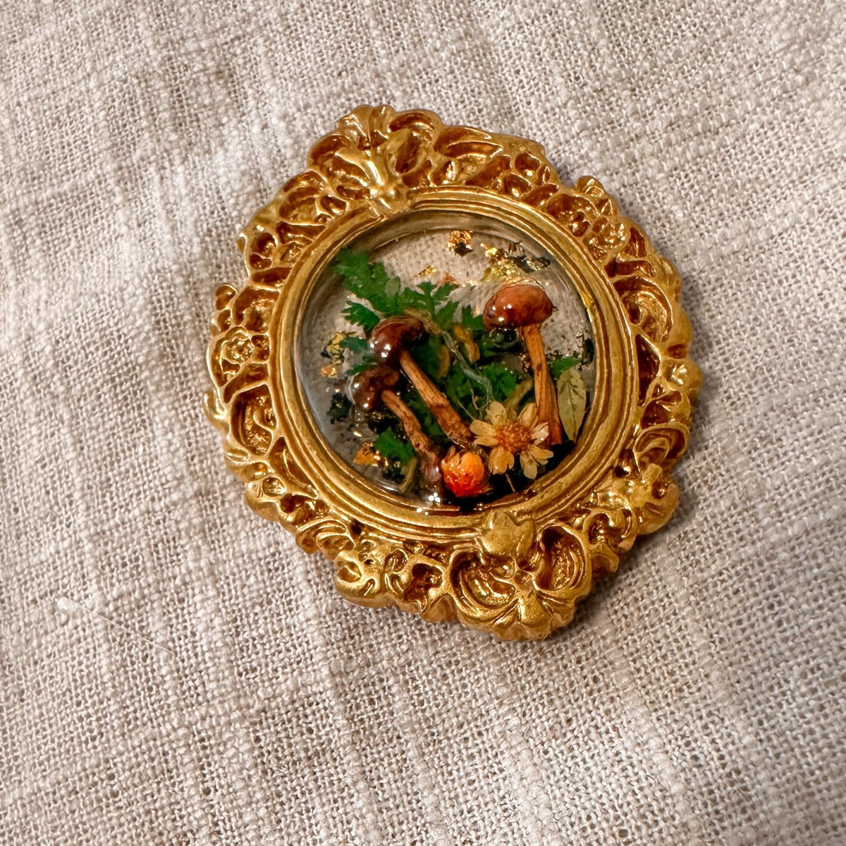 Detail of the ornate gold scrollwork frame on the mushroom fridge magnet