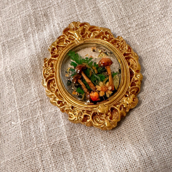 Detail of the ornate gold scrollwork frame on the mushroom fridge magnet