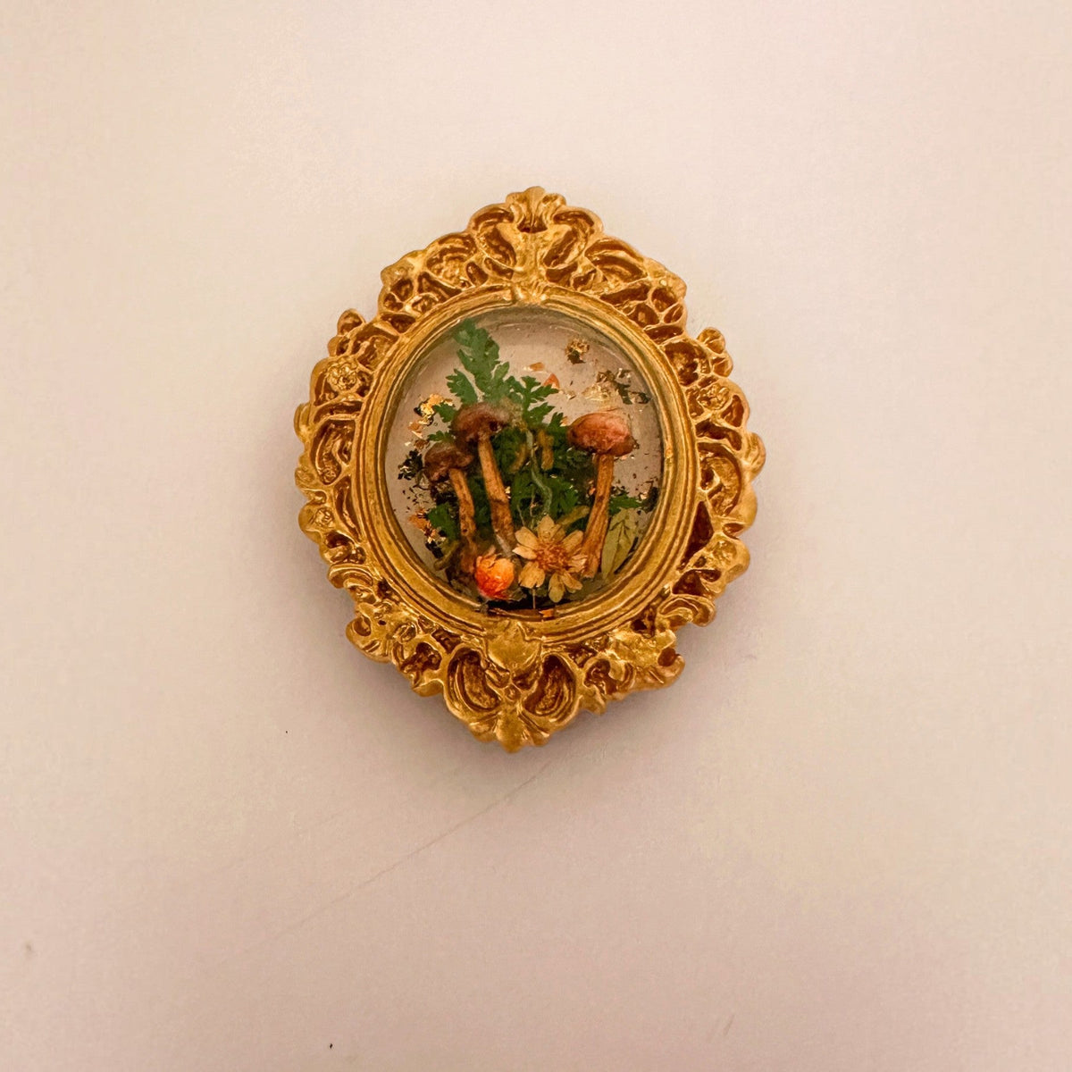 Mushroom fridge magnet with gold leaf flecks catching the light through the clear resin