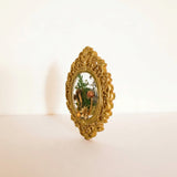 Mushroom fridge magnet standing upright in its ornate gold frame against a soft white background