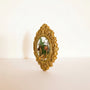 Mushroom fridge magnet standing upright in its ornate gold frame against a soft white background