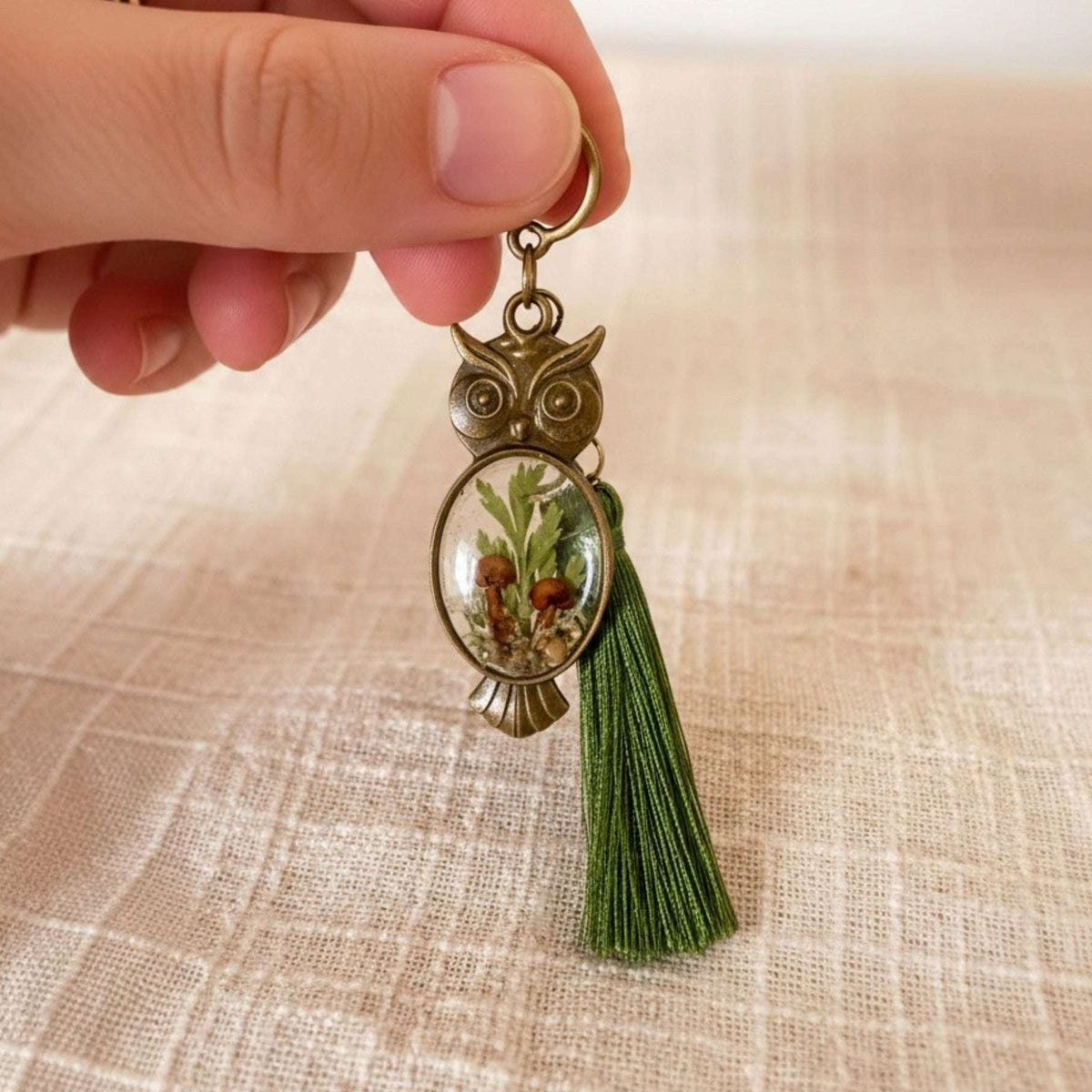 Antique bronze mushroom owl keychain held in a hand showing its 2 inch size