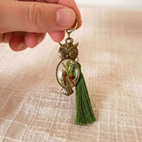 Antique bronze mushroom owl keychain held in a hand showing its 2 inch size