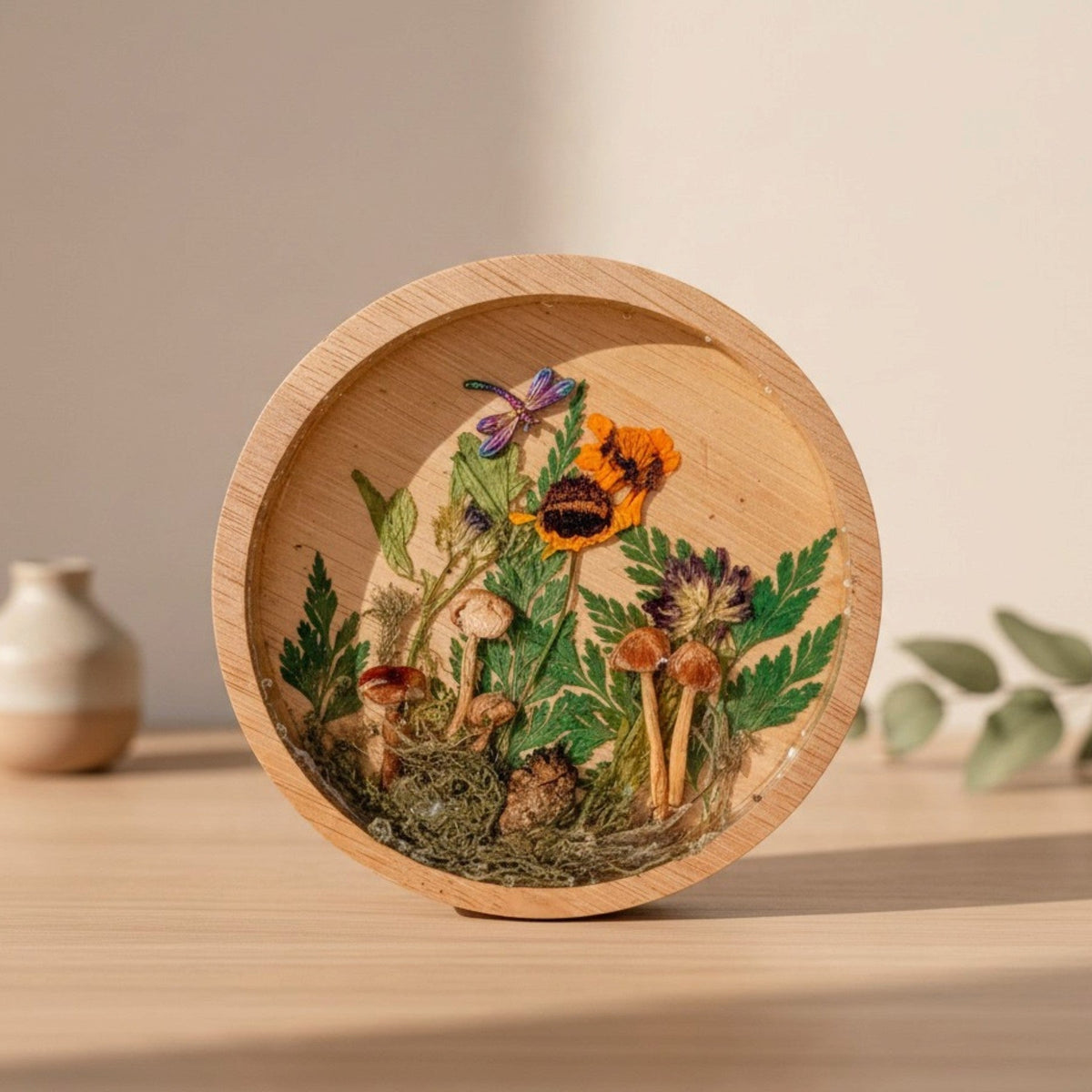 mushroom trinket dish in a round natural wood rim with clear resin, raised mushrooms, moss, ferns and bright flowers
