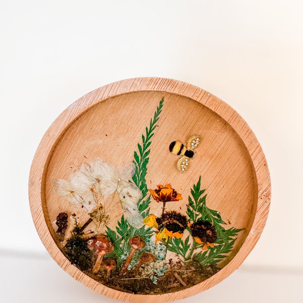 Mushroom trinket dish in a round natural wood rim with clear resin, tiny mushrooms, pressed flowers, greenery and a bee charm
