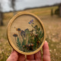 Mushroom trinket dish with a round natural wood rim, clear resin, raised mushrooms, dried botanicals and dragonfly charm