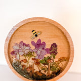 mushroom trinket dish in a round natural wood tray with clear resin, preserved purple flowers, moss and bee charm