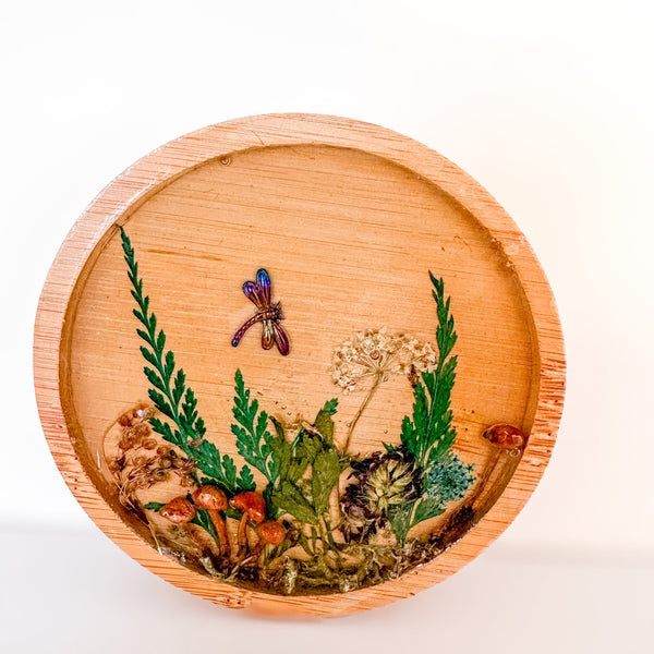 mushroom trinket dish with a round natural wood rim, clear resin, raised mushrooms, pressed ferns and a dragonfly charm