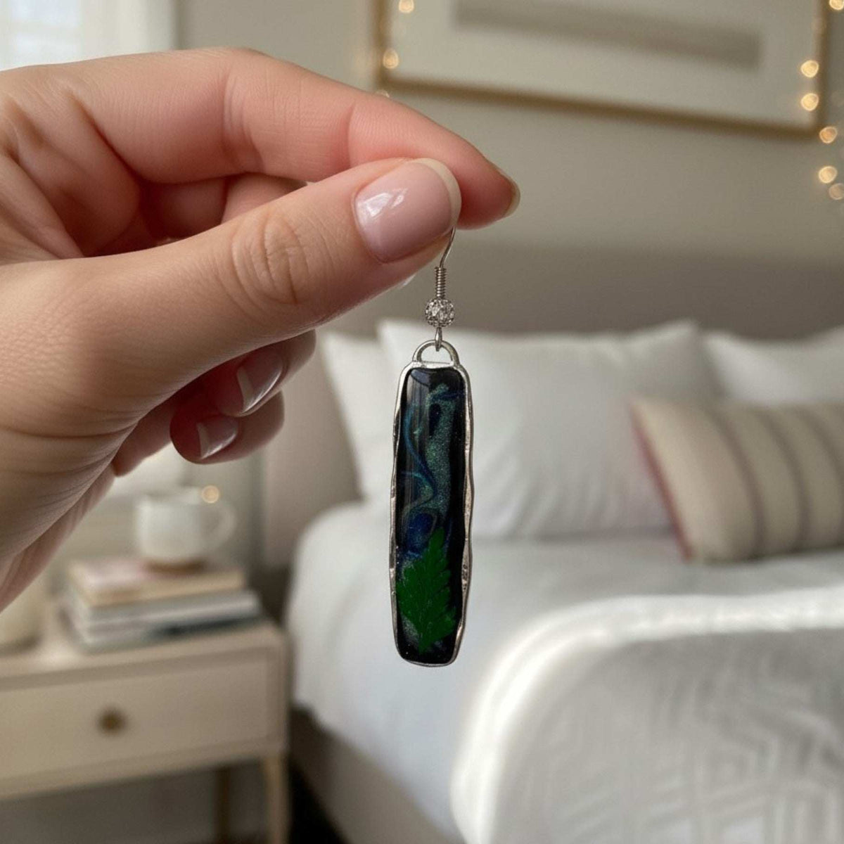 Close-up of the hand-poured "sky" resin showing swirls of blue and green Northern Lights effects above a tiny preserved fern.