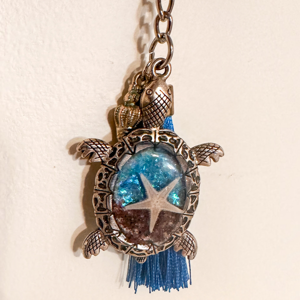 Ocean Keeper sea turtle keychain with antique bronze metal shell frame, blue resin, starfish centerpiece and blue tassel