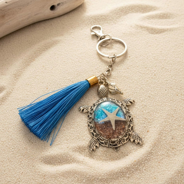 Ocean Keeper sea turtle keychain with antique bronze metal edging, blue resin, sandy shell details, and a bright blue tassel