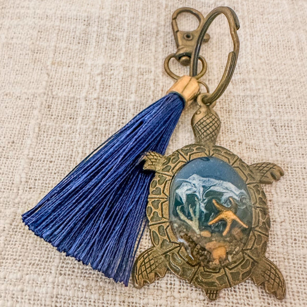 Ocean Keeper sea turtle keychain with antique bronze turtle frame, dark blue tassel and ocean-toned resin center