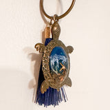 Ocean Keeper turtle keychain in antique bronze metal with a glossy blue resin shell, dark tassel and coastal charms