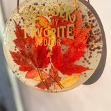 October Glow round resin wall art with red and orange maple leaves, copper glitter and gold lettering