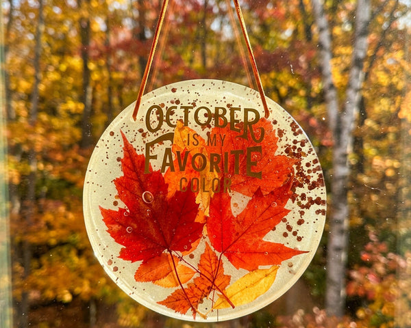 October Glow round resin wall art with vivid red and orange maple leaves, copper flecks, and autumn lettering