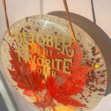October Glow round maple leaf resin wall art with vivid red leaves, copper glitter and gold lettering