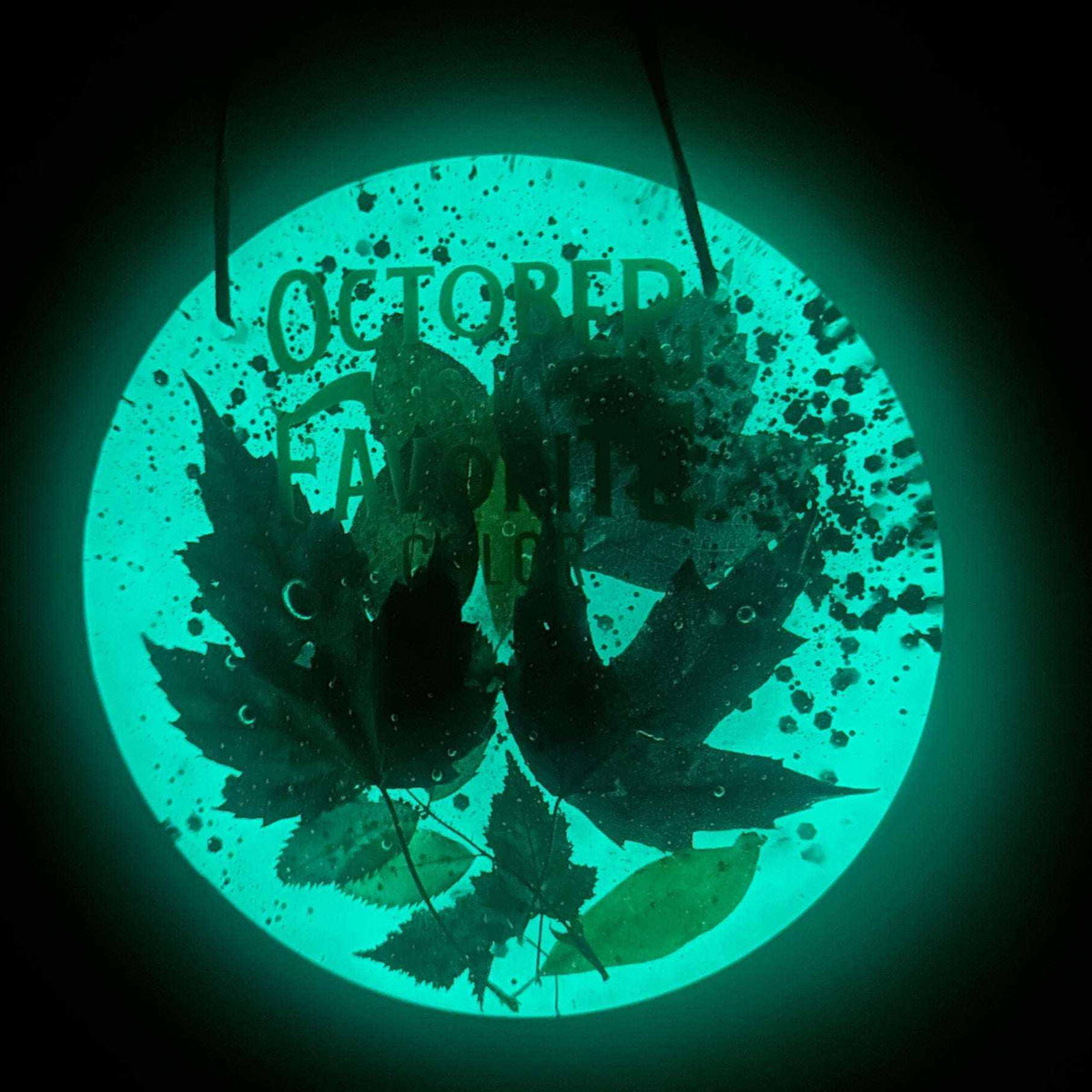 October Glow maple leaf resin wall art with dark preserved leaves and lettering against a vivid turquoise glow