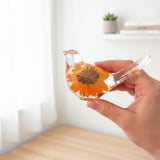 Small clear resin bird decor with a bright orange sunflower encased inside and delicate floral accents, showcasing an orange sunflower design.