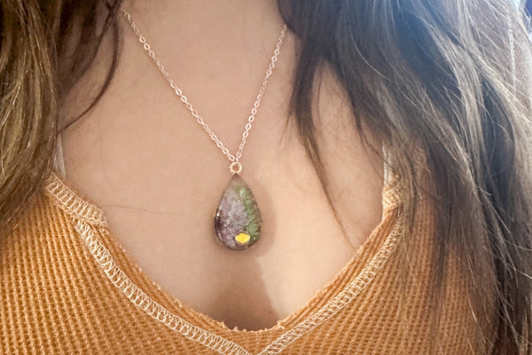 Person wearing a necklace with an tear drop-shaped pendant