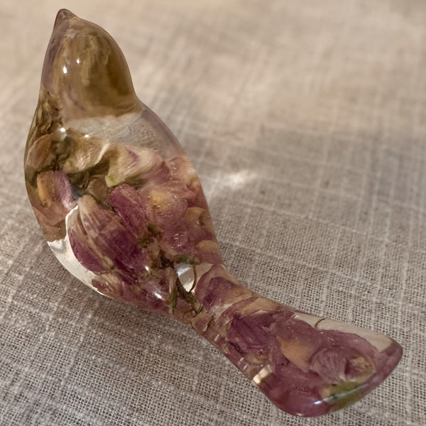 pink lupine resin bird figurine in glossy clear resin, with preserved mauve-pink flowers throughout and a flower-filled crown and tail