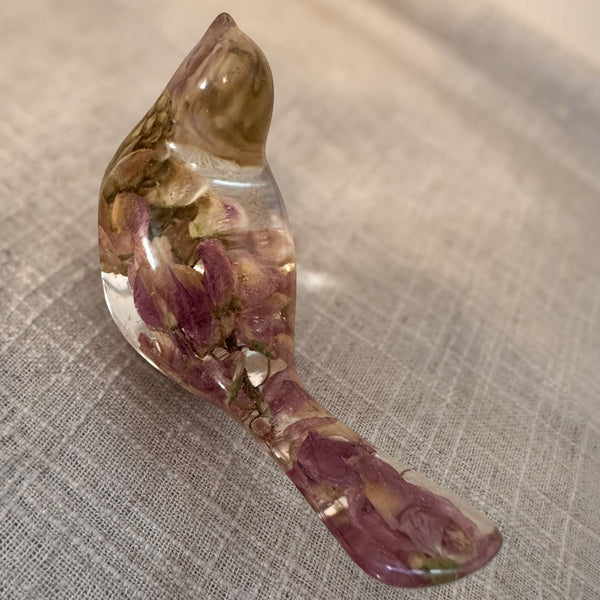 Pink lupine resin bird figurine in clear glossy resin, with preserved pink-purple flowers and a pointed crown rising through its head.
