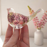 pink lupine resin bird decor in clear resin, with dimensional rose and dusty pink blooms and a green fern in its tail