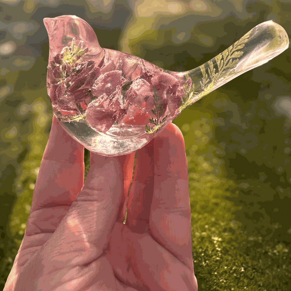 Pink lupine resin bird decor with translucent clear resin, pink dried flowers, green foliage in the tail, and a glittered base