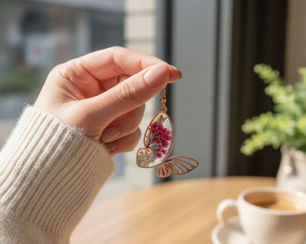 Rose gold Garden Wing Earrings with pressed deep pink and white flowers in resin butterfly wings and gold butterfly accent