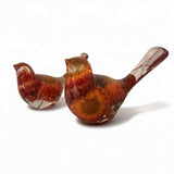 Resin Bird Pair with amber-clear bodies, rust-red and orange dried flowers, and long sculpted tails.