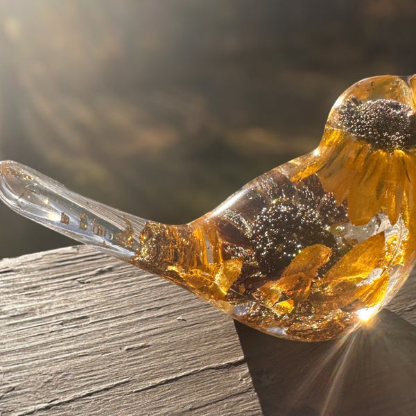 Black eyed susan resin bird figurine in clear amber resin, with preserved golden petals, dark centres and gold-flecked tail.