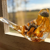 Black eyed susan resin bird in clear resin, with golden layered petals, dark centres and gold leaf accents along the tail and base.