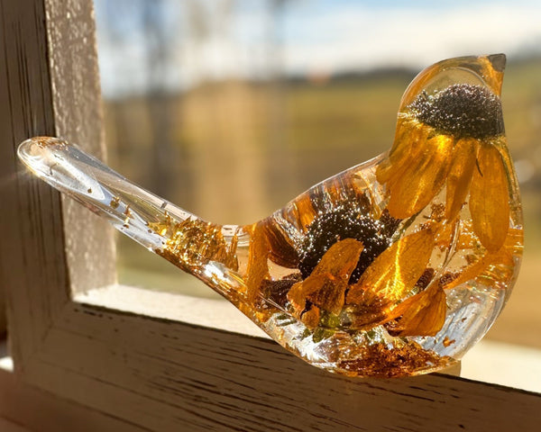 Black eyed susan resin bird in clear resin, with golden layered petals, dark centres and gold leaf accents along the tail and base.
