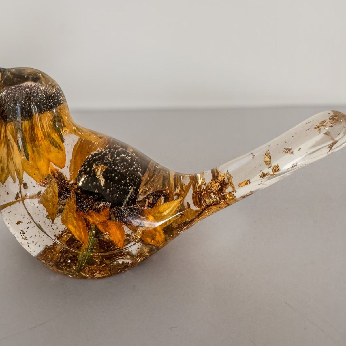 Black eyed susan resin bird with clear glossy resin, golden petals, dark brown centres and gold leaf accents in its tail and base.