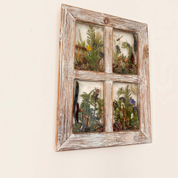Pressed flower window art in a distressed whitewashed wood frame, with four clear resin panes of pressed ferns and colorful botanicals