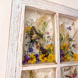 Holographic backing shifting colour behind the petals of the pressed flower window art