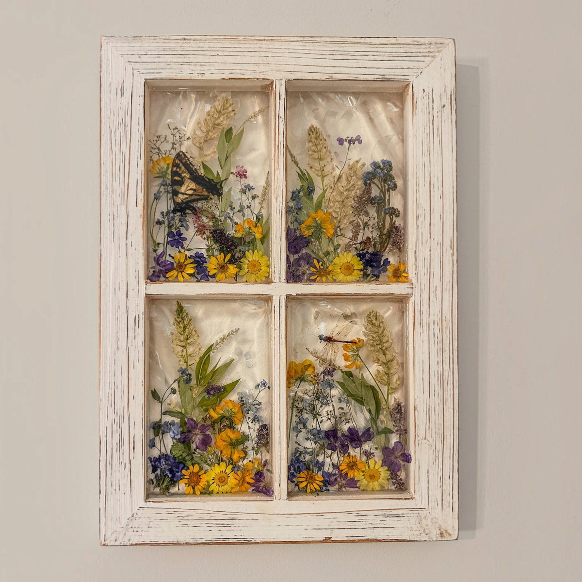 Pressed flower window art showing the dragonfly resting among the blooms in the lower pane