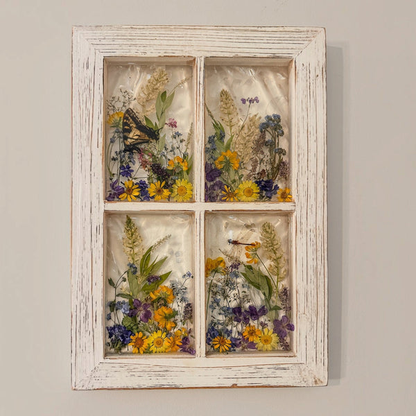 Pressed flower window art showing the dragonfly resting among the blooms in the lower pane