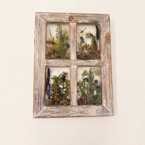 Pressed flower window art in a weathered whitewashed wood frame, with four clear panes of layered ferns and colorful dried flowers