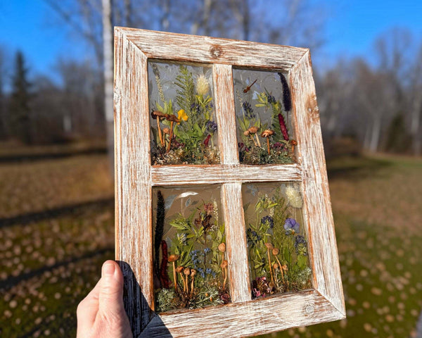 Pressed flower window art in a whitewashed wood frame, with four clear resin panes filled with colorful flowers and greenery