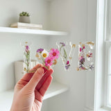 Wildflower resin LOVE word art with pink daisies, purple wildflowers, rose buds, and gold leaf flakes