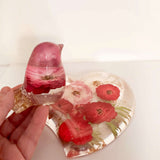 rose heart trinket dish in clear resin with pressed red and pink roses and green leaves, paired with a rose-filled songbird