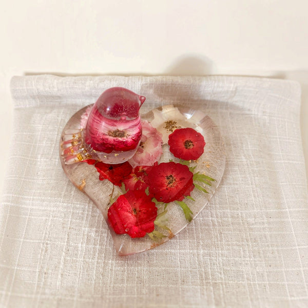 Rose heart trinket dish in clear resin with pressed red and pink roses, green leaves, gold flecks and a matching pink songbird