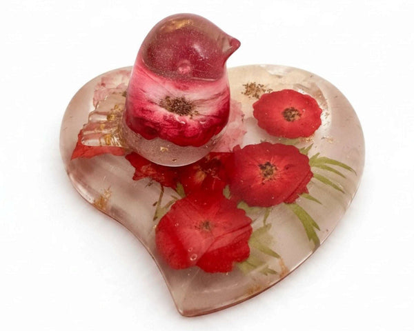 rose heart trinket dish in clear resin with red pressed roses, green botanicals, gold leaf and a matching rose-filled bird