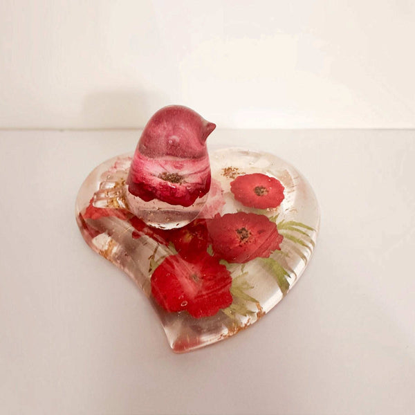 Rose heart trinket dish in clear resin with pressed red roses, green botanical accents and a matching pink songbird