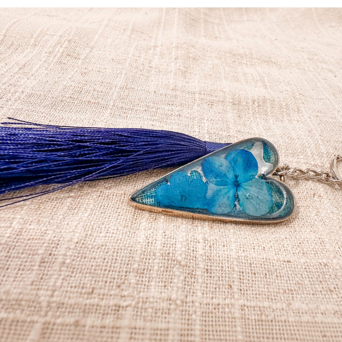Sapphire Heart keychain with vivid blue flowers preserved in a silver-edged resin heart and a navy tassel