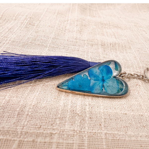 Sapphire Heart keychain with vivid blue flowers preserved in a silver-edged resin heart and a navy tassel